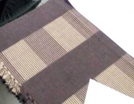 A brown and cream yarn-dyed check with a knotted fringe, laid on a white table.