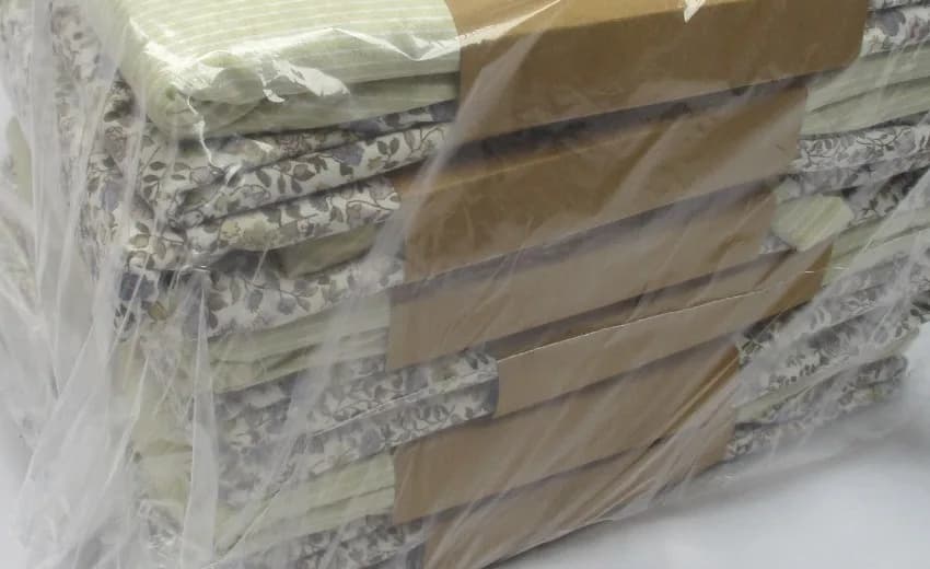A finished lot of folded printed cotton, banded in kraft paper and wrapped in clear film.