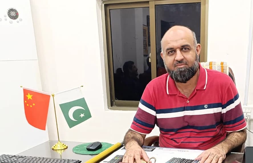 Humayun at his desk, with Pakistan and China desk flags beside him.