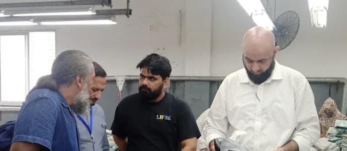 A group leaning over a work table reviewing goods together on a factory floor.